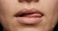 Primer plano de una persona humedeciendo sus labios resecos con la lengua.
